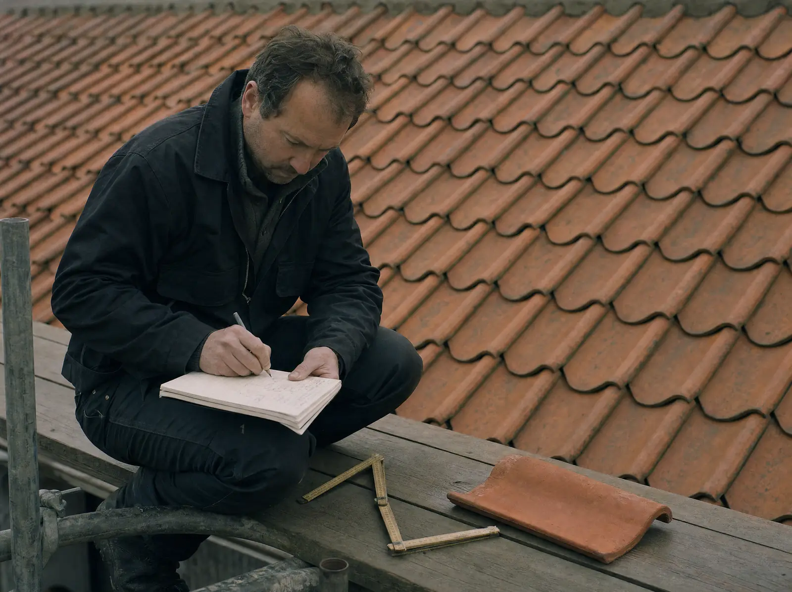 Roofer measuring a pitched roof before preparing a written quote